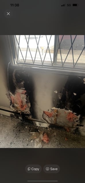 Damaged basement wall with peeling paint and rust stains near a window with metal grille